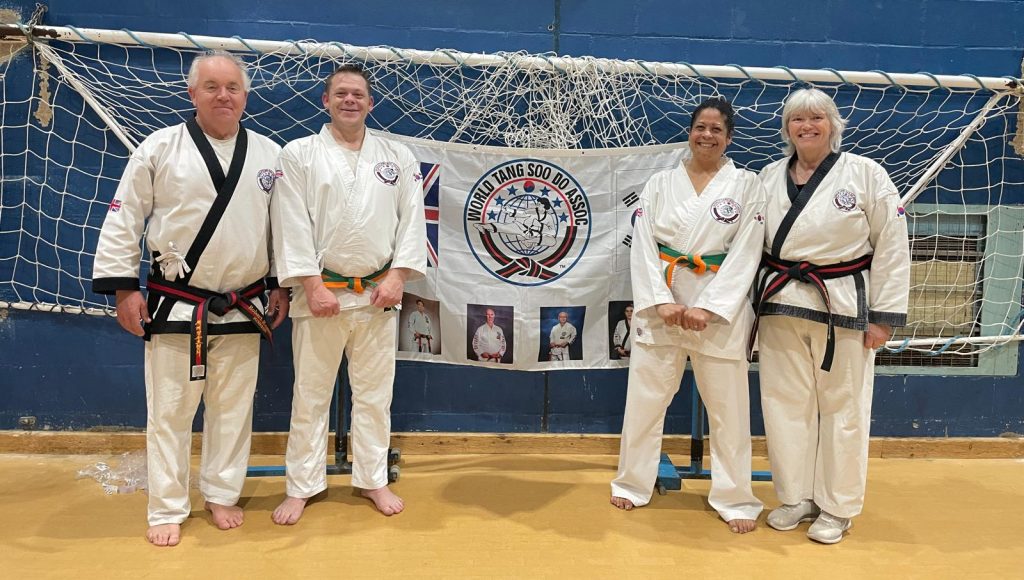 Tang Soo Do students and instructors in front of association flag showing new belts