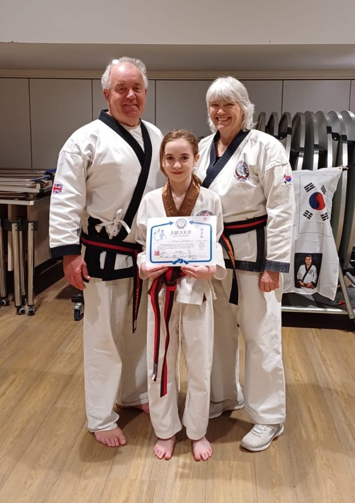 Tang Soo Do students and instructors in front of association flag showing new belts