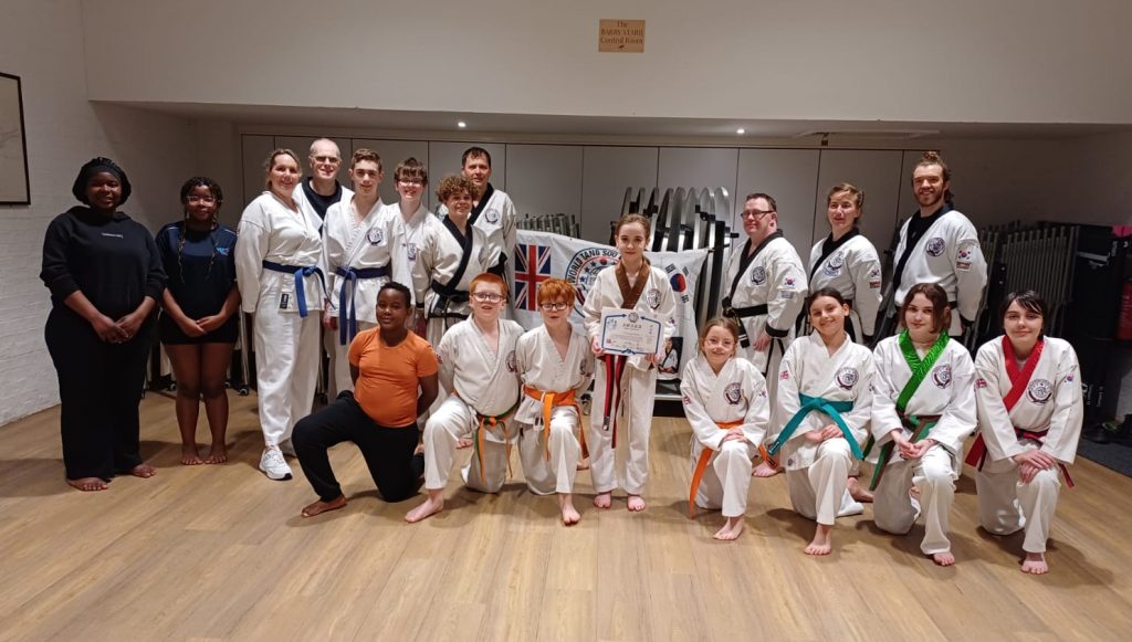 Tang Soo Do students and instructors in front of association flag showing new belts