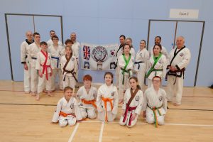 Tang Soo Do students and instructors in front of association flag showing new belts