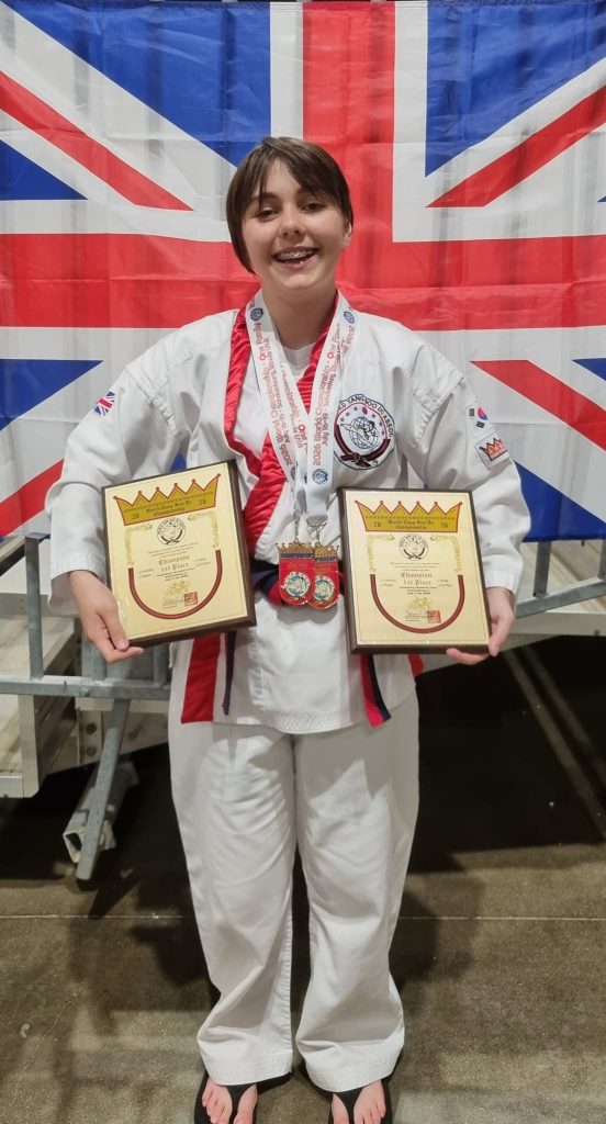 Philippa holding two 1st-place plaques and medals, Union Jack flag behind