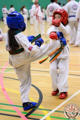 Two junior students sparring, wearing head and hand protection, at the club's August 2026 clinic