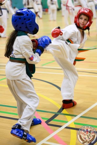 Two junior students sparring with a high kick at the club's August 2026 clinic