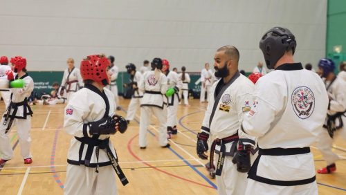 Black belt students standing in pairs before sparring at the club's August 2026 clinic