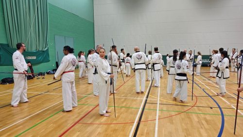 Students practising with bo staffs during a weapons session at the club's August 2026 clinic