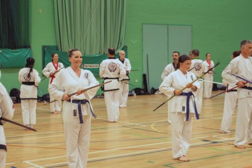 Students holding bo staffs during weapons practice at the GBTSDA clinic in August 2026