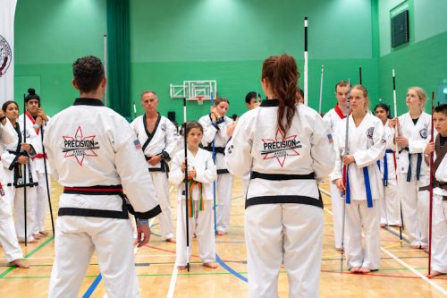 Students watching a bo staff demonstration in a semicircle at the August 2026 GBTSDA clinic